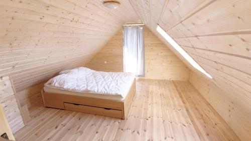 małe łóżko w drewnianym pokoju z oknem w obiekcie Chata Wilka - całoroczny dom z bali na wyłączność z 3 sypialniami w mieście Brzegi Dolne