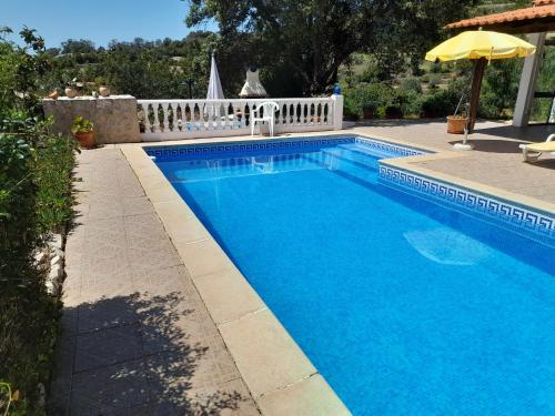 einen Pool mit Sonnenschirm neben einem Haus in der Unterkunft Casa dos Amigos - NEW management in Estói
