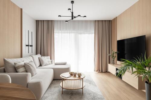 a living room with a white couch and a tv at Stary Tartak nad jeziorem Drwęckim - MAZURIA APARTAMENTY in Ostróda