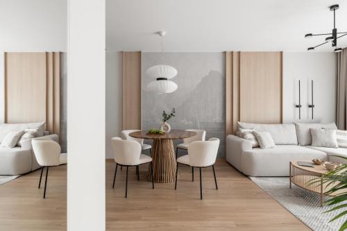 Mazuria Apartament nad jeziorem Drwęckim في أوسترودا: غرفة معيشة مع أريكة بيضاء وطاولة وكراسي