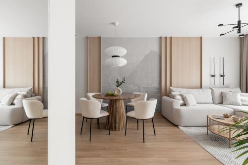 a living room with a white couch and a table and chairs at Stary Tartak nad jeziorem Drwęckim - MAZURIA APARTAMENTY in Ostróda