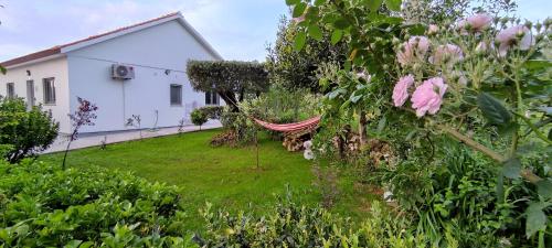 a garden with a hammock in front of a house at Casa Dos Vales 11 in Porto de Mós