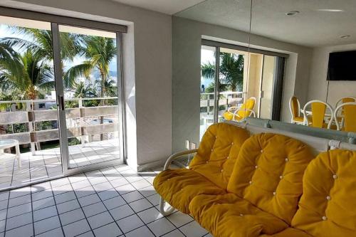 sala de estar con sofá amarillo y balcón en Condominio en zona turística en Acapulco