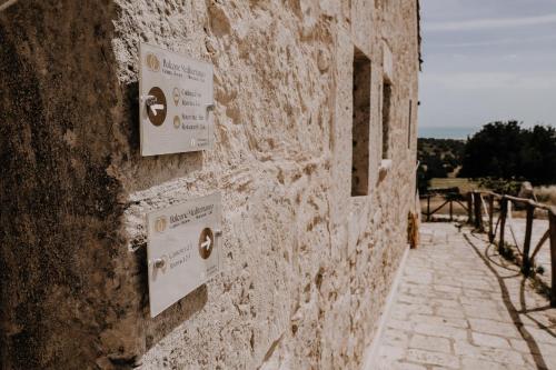 un edificio de piedra con letreros en el costado en Agriturismo Balcone Mediterraneo - Camere, en Ragusa