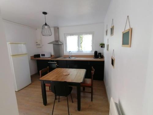 a kitchen with a wooden table and a refrigerator at Logement Soulac-sur-mer 4 personnes in Soulac-sur-Mer