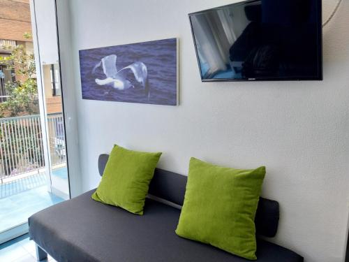 - un canapé avec 2 oreillers verts dans l'établissement APARTAMENTO con TERRAZA VISTAS AL MAR, à Lloret de Mar