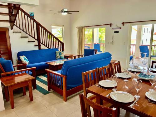 a dining room with a blue couch and tables and chairs at VeLento Partial Ocean View Penthouse #7 in Caye Caulker