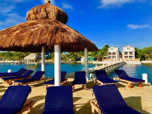 a group of chairs and an umbrella and a pool at VeLento Partial Ocean View Penthouse #7 in Caye Caulker