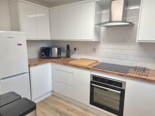 a kitchen with white cabinets and a stove top oven at Spacious Town House - Coventry City Centre, Free Parking, Sleeps 6, High-Speed WiFi, En-suite, Great Location, A45, A46, JLR, NEC, Airport, Warwick & Stratford Upon Avon - Fernwood Stays - Your home away from home! in Coventry