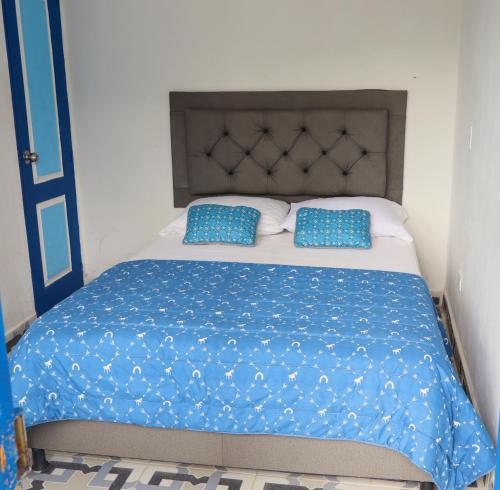 a bed with blue pillows on top of it at Vista Farallones Hostel in Jardin