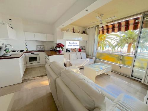 Una sala de estar con un sofá blanco y una cocina. en 2p front de mer bocca cabana, en Cannes