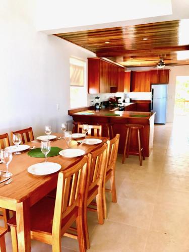 a dining room with a wooden table and a kitchen at VeLento Oceanfront Penthouse #3 in Caye Caulker