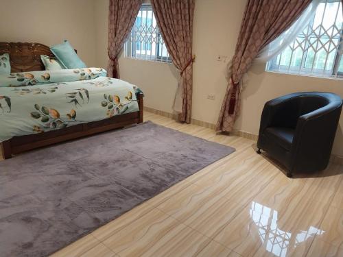 ein Schlafzimmer mit einem Bett und einem schwarzen Stuhl in der Unterkunft EuChris Homes in Kumasi