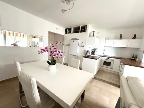 una cocina blanca con una mesa blanca con flores. en 2p front de mer bocca cabana, en Cannes