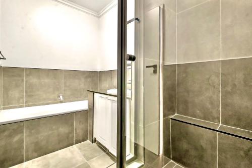 a bathroom with a shower and a tub and a sink at Sandton Lux, CBD, 2 Bedroom & 2 Ensuite, No Load shedding in Johannesburg