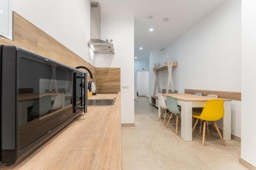 a kitchen with a large tv and a table with yellow chairs at CMDreams Platinium- Apartamentos turísticos en el centro de Mérida in Merida