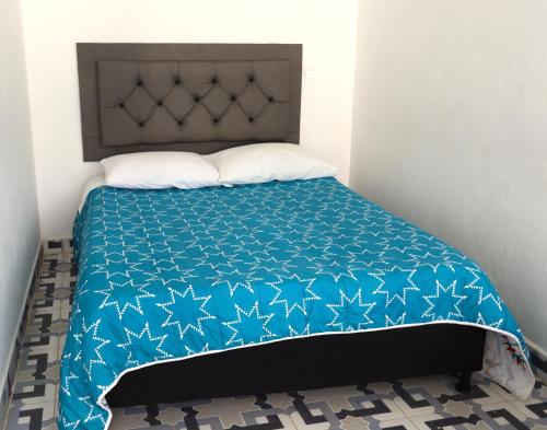 a bed with a blue comforter and white pillows at Vista Farallones Hostel in Jardin