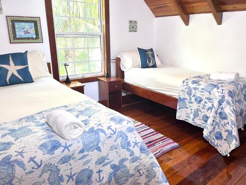 Un dormitorio con dos camas y una ventana. en Barbara's Beach House, en Caye Caulker