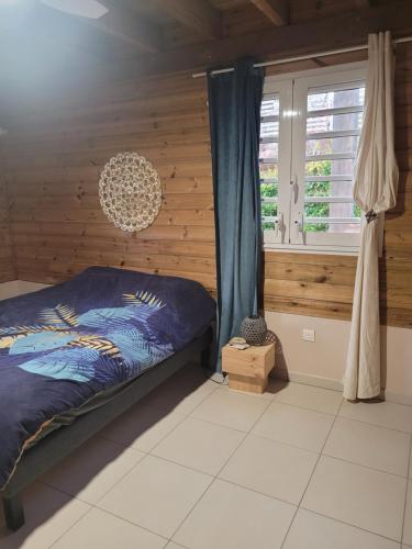 a bedroom with a bed with a wooden wall at VILLA -Le Chalet Tropical in Le Marin