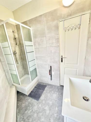 a white bathroom with a shower and a sink at L'Eden d'Argenteuil in Argenteuil