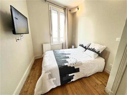 a bedroom with a bed and a tv on the wall at L'Eden d'Argenteuil in Argenteuil