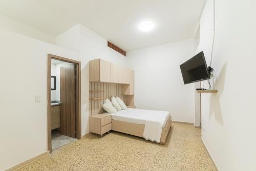 um quarto branco com uma cama e uma televisão em Loft Urbano en Medellín Pet Friendly 105 em Medellín