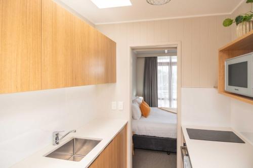 een keuken met een wastafel en een bed in een kamer bij Whispering Sands Beachfront Motel in Gisborne