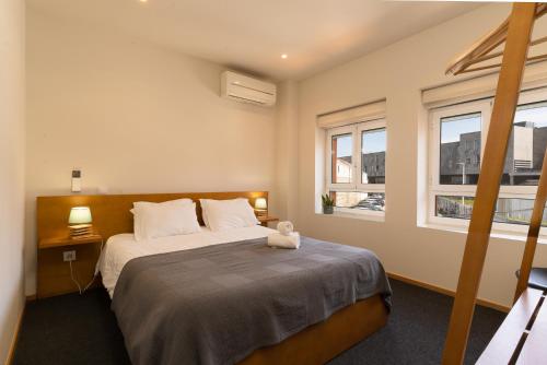 Peach Hostel & Suites في بورتو: غرفة نوم بسرير كبير مع نافذتين