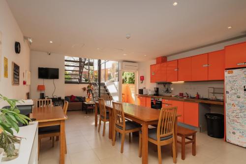 Peach Hostel & Suites في بورتو: مطبخ مع خزائن برتقال وطاولة وكراسي