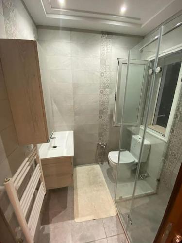 uma casa de banho com um WC e uma cabina de duche em vidro. em Nouvel appartement jamais habité em Hammamet Nord