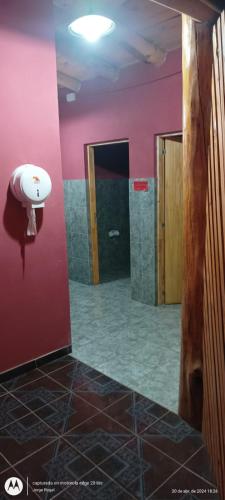 a bathroom with a pink wall with a toilet paper holder at Camping El Bosque in El Hoyo