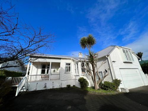 een wit huis met een palmboom ervoor bij La Casa Bonita Auckland in Auckland