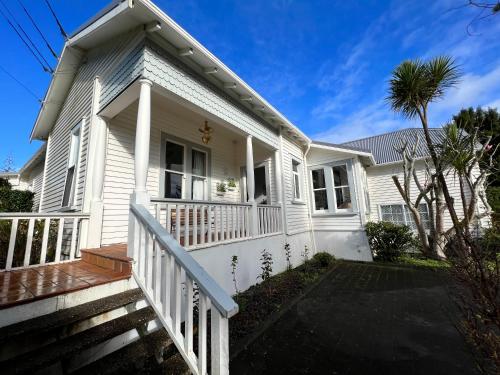 een wit huis met een wit hek en een veranda bij La Casa Bonita Auckland in Auckland