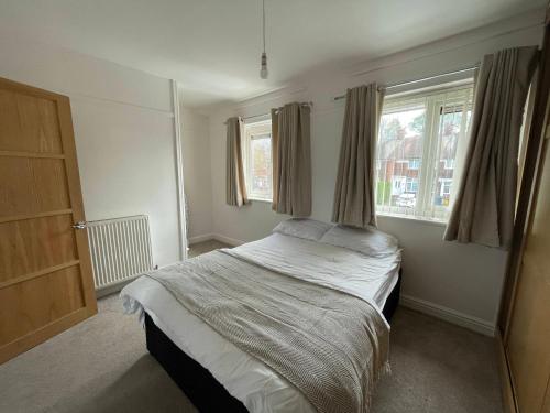 a bedroom with a bed and two windows at 2BR 15 min to BHX Airport 5 min to Heartlands in Birmingham