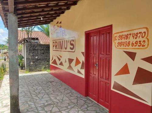un edificio con una puerta roja a un lado. en Hotel Primu's en Novo Airão