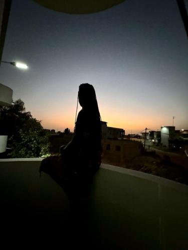 a woman sitting on a ledge looking at the sunset at keur manga2 in Somone