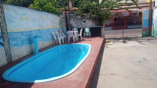 a blue swimming pool with chairs and a fence at Pousada Maria Bonita in Paripueira