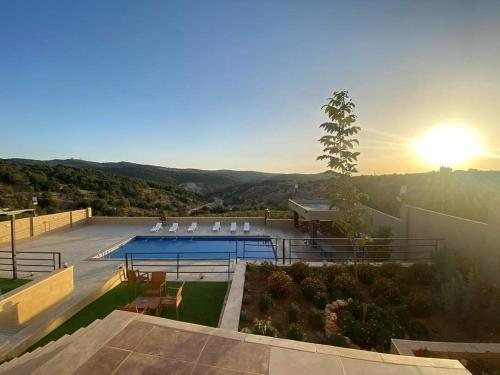 a house with a swimming pool with the sun setting at Mountain farm in Ajloun