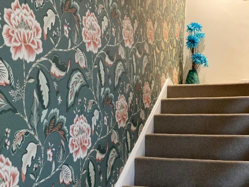 a stairway with a floral wallpaper on the wall at Luxury Contractors Group Stay FAST Wifi FREE Parking in Bedford