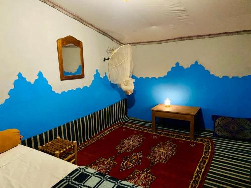 a room with a blue wall with a table and a bed at Auberge L'oasis Mhamid in Mhamid