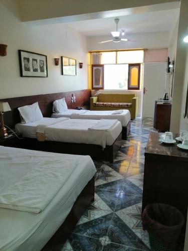 a hotel room with two beds and a couch at Rezeiky Hotel & Camp in Luxor