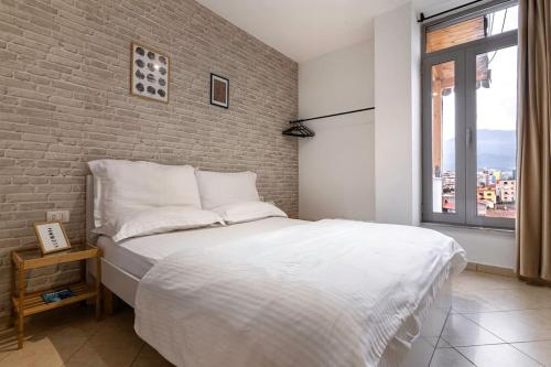 a bedroom with a white bed and a brick wall at NEW BAZAAR Apartment in Tirana