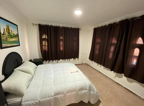 a bedroom with a large white bed and windows at Villa El Ghriss in Bine el Ouidane