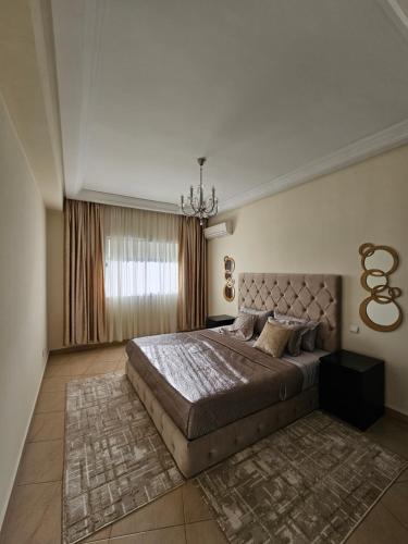 Un dormitorio con una cama grande y una lámpara de araña. en appartement familiale tanger R, en Tánger