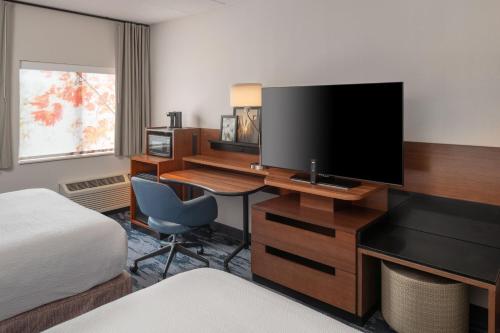 a hotel room with a desk with a tv and a bed at Fairfield Inn Boston Tewksbury/Andover in Tewksbury