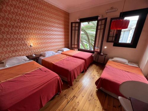 a room with three beds and a window at APARTHOTEL POVIDENCIA Santiago in Santiago