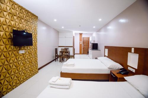 Habitación de hotel con 2 camas y TV en coastal hotel, en Iloilo City
