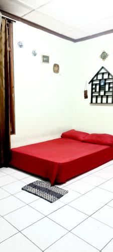 een slaapkamer met een rood bed in een kamer bij HOMESTAY SYARIAH ENDRA JATI in Tjepit