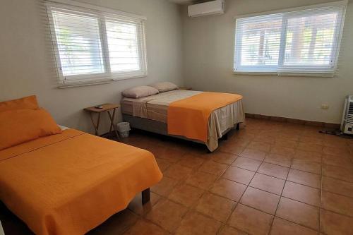 1 Schlafzimmer mit 2 Betten und 2 Fenstern in der Unterkunft Welcome to The Beach House in Playa Pochomil