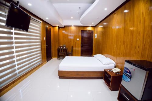 um quarto com uma cama e uma televisão em coastal hotel em Iloilo
